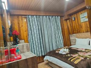 ein Schlafzimmer mit einem Bett in einem Zimmer mit Holzwänden in der Unterkunft Hotel Olive Branch Darjeeling Near Mall Road - Excellent Customer Service - Parking Facilities - Best Seller in Darjeeling