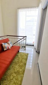 ein Wohnzimmer mit einem roten Sofa und einem grünen Teppich in der Unterkunft Vila Mulyo cordoba residence E4 in Tlekung