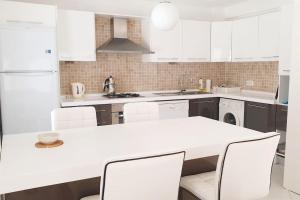 uma cozinha branca com uma mesa e cadeiras brancas em Seaview (Sunset & Greek-Islands) Luxury Apartment em Bodrum City