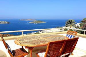 uma mesa de madeira e cadeiras numa varanda com o oceano em Seaview (Sunset & Greek-Islands) Luxury Apartment em Bodrum City