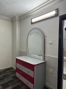 baño con tocador rojo con espejo en شقة مفروشة للايجار, en Irbid