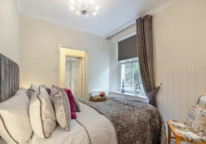 1 dormitorio con cama con almohadas y ventana en Seashells, en Saundersfoot