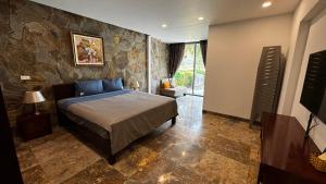 1 dormitorio con cama y pared de piedra en Flamingo Đại Lải Resort - Bách Thanh C16, en Phúc Yên