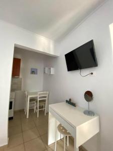 a living room with a white table and a tv on the wall at The Garden Studio in Kriopigi