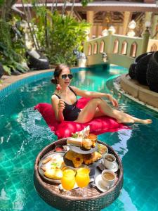 una mujer sentada en una piscina con una bandeja de comida en Quality Beach Resorts and Spa Patong en Patong