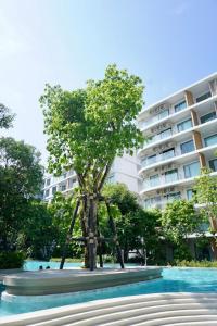 een boom voor een groot gebouw bij Phyll Phuket 1 Bedroom 1 Bathroom Central Phuket in Ban Rangeng