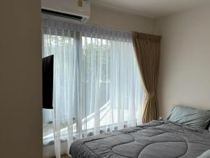 een slaapkamer met een bed en een groot raam bij Phyll Phuket 1 Bedroom 1 Bathroom Central Phuket in Ban Rangeng