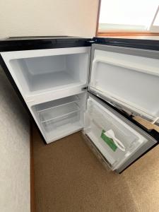 un réfrigérateur vide avec une porte ouverte dans une pièce dans l'établissement 松ノ木ハウス, à Nobeji