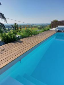una piscina con una terraza de madera y flores en Gîte le Chêne du Py, en Villié-Morgon