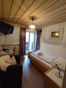Habitación con cama, silla y TV. en Garni Hattlerhof B&B, en Brunico
