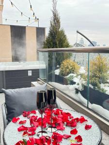 a table with two wine glasses and red roses on it at Luxury apartment with jacuzzi Pechersk Plaza in Kyiv