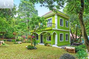 a green and white house with a yard at Cerf Volant Soc Son Resort in Hanoi