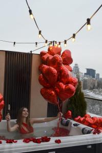 a woman in a tub with a bunch of red balloons at Luxury apartment with jacuzzi Pechersk Plaza in Kyiv