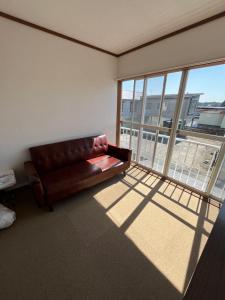 ein Ledersofa in einem Zimmer mit einem großen Fenster in der Unterkunft 松ノ木ハウス in Nobeji