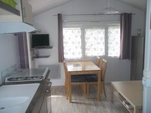 una pequeña cocina con mesa, mesa y ventana en camping aire du gros pré, en Lesseux