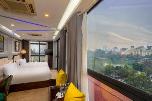 um quarto com uma cama e uma grande janela em Bella Rosa Hotel & Travel em Hanói