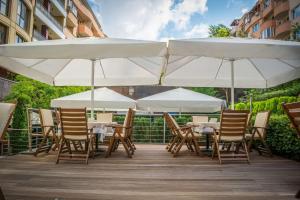 a row of tables and chairs with white umbrellas at Best Western Plus Olives City Hotel - Free Parking in Sofia
