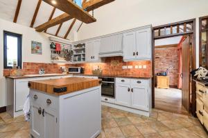 a kitchen with white cabinets and a brick wall at Finest Retreats - Flint Barn in Faversham
