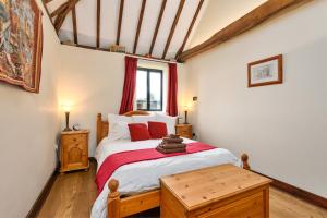 a bedroom with a bed with red pillows at Flint Barn in Faversham