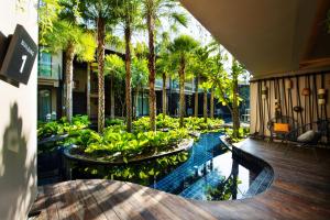 a swimming pool with palm trees in a building at Luminous Resort & Spa by Areca in Phuket Town