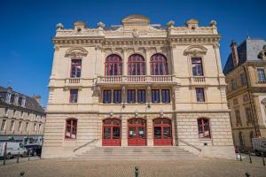 um grande edifício de pedra com portas vermelhas e escadas em Contact Hôtel de la Gare et son restaurant Côte à Côte em Autun