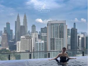 a woman in a infinity pool on the roof of a building at The Luxe KLCC View Sky Pool in Kuala Lumpur