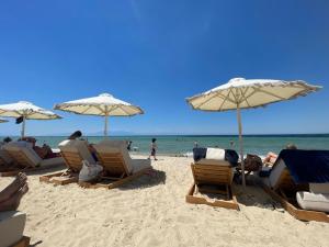 een groep stoelen en parasols op een strand bij Fterna Apartment in Perea