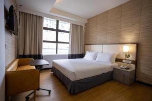 a hotel room with a bed and a chair at Citrus Hotel Johor Bahru by Compass Hospitality in Johor Bahru