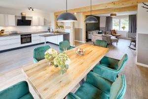 a kitchen and living room with a wooden table and green chairs at Landgut Basthorst in Crivitz