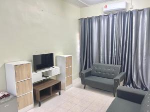sala de estar con silla y TV en Homestay Harmoni With Wifi and Android TV, en Pekan