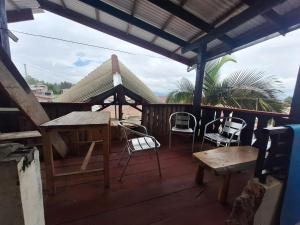 a wooden deck with chairs and a table and a bench at Smiley's Homestay in Berastagi