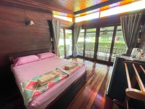 a bedroom with a bed in a room with windows at Ruen Orathai Resort in Prachuap Khiri Khan