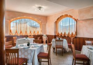 una sala da pranzo con tavoli e sedie e due finestre di Hotel La Fenice a Castel di Sangro