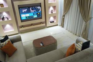 ein Wohnzimmer mit einem Sofa und einem Flachbild-TV in der Unterkunft Central/3 bed/Private & Equipped in Madinat as-Sadis min Uktubar