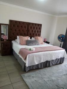 - une chambre avec un grand lit et des oreillers roses dans l'établissement Gold Guesthouse and conferences, à Welkom