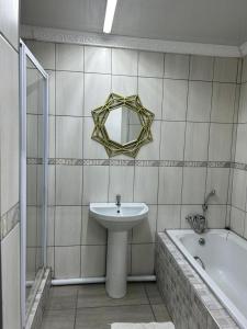 La salle de bains est pourvue d'un lavabo, d'un miroir et d'une baignoire. dans l'établissement Gold Guesthouse and conferences, à Welkom