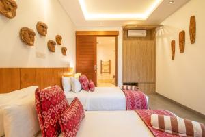 a hotel room with two beds with red and white pillows at Exquisite 4br Haven, 5min Stroll To Beach Canggu in Canggu
