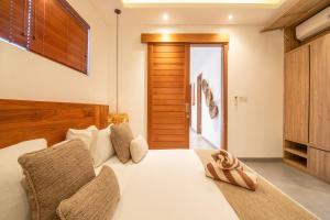 a bedroom with a large white bed with a wooden headboard at Exquisite 4br Haven, 5min Stroll To Beach Canggu in Canggu