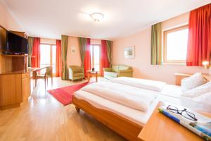 a bedroom with a large bed and a living room at Hotel Alte Post Südsteiermark in Leibnitz