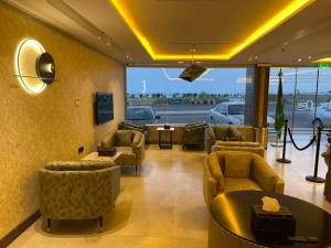 uma sala de estar com sofás e cadeiras e uma grande janela em حياة تاون 3 em Umm Lajj