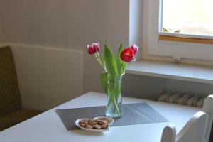 eine Vase mit Blumen und eine Schüssel Kekse auf dem Tisch in der Unterkunft De grote Linde in Heiligenhafen