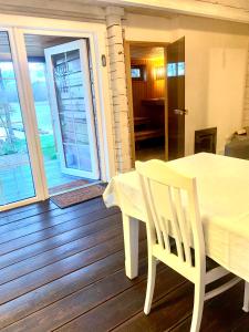 Aviliai的住宿－Sodyba Paukščių Takas，铺有木地板并设有阳台的白色桌椅