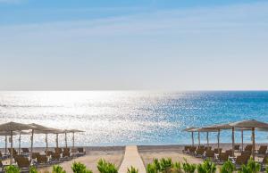a beach with chairs and umbrellas and the ocean at Elysium Resort & Spa in Faliraki