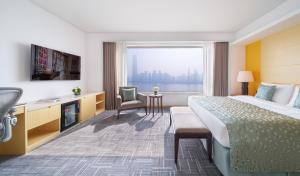 a hotel room with a bed and a large window at Marco Polo Wuhan in Wuhan