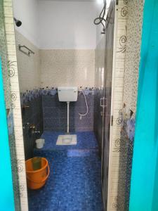 uma casa de banho com um piso azul e um WC. em JHARANA GUEST HOUSE em Puri