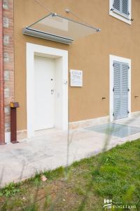 un edificio con una puerta blanca y dos ventanas en TENUTA FOGLIANI en Visciano