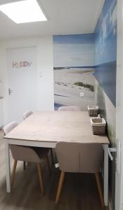 een eettafel met stoelen en een schilderij van het strand bij Duin en Zee Texel in De Koog