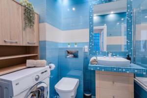 a blue tiled bathroom with a washing machine and a sink at Grapefruit Apartment Skorosze in Warsaw