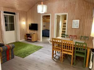 a living room with a table and chairs and a television at Fiskebäckgårds gästhus in Lysekil