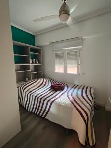 a bedroom with a striped bed and a window at Paul's Rooms, no se admiten turistas not for tourists in Valencia